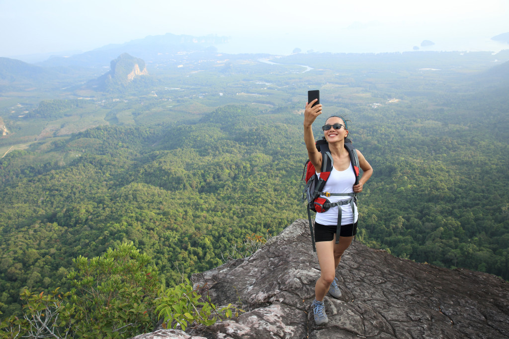 woman hiker taking photo with smart phone at mountain peak